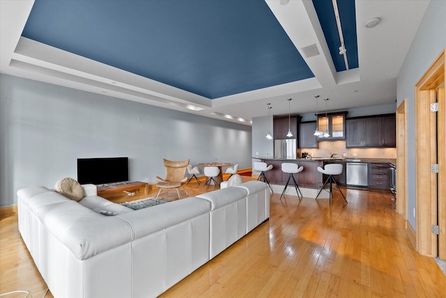 living room featuring light hardwood / wood-style floors and a raised ceiling