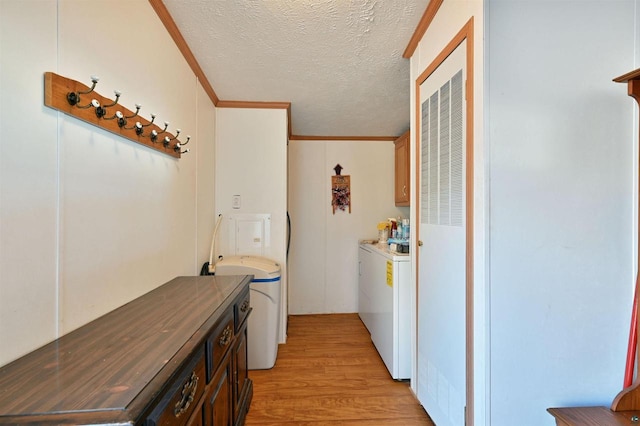 washroom featuring cabinets, light hardwood / wood-style flooring, ornamental molding, a textured ceiling, and washer / clothes dryer