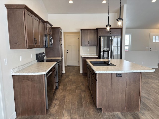 kitchen with sink, dark brown cabinets, hanging light fixtures, a center island with sink, and appliances with stainless steel finishes