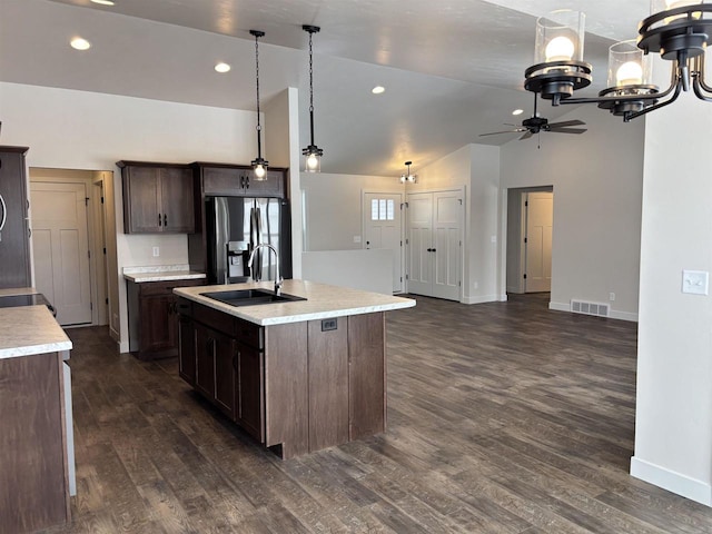 kitchen featuring dark brown cabinetry, sink, hanging light fixtures, a center island with sink, and stainless steel fridge