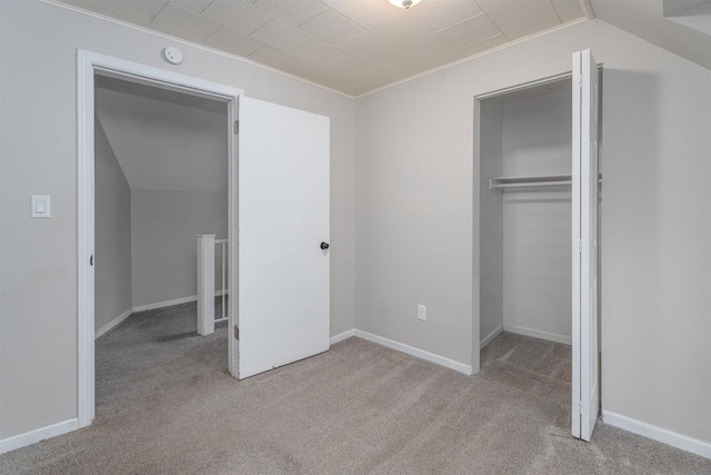 unfurnished bedroom featuring light carpet, a closet, and lofted ceiling