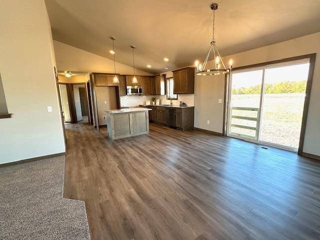 kitchen with pendant lighting, dark wood-type flooring, vaulted ceiling, a notable chandelier, and a kitchen island