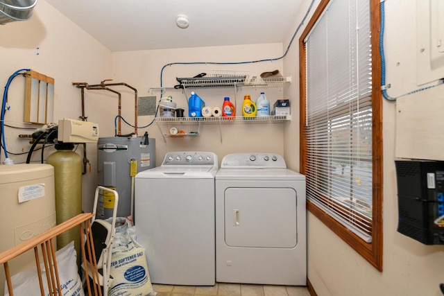 washroom featuring washer and clothes dryer, light tile patterned flooring, and water heater