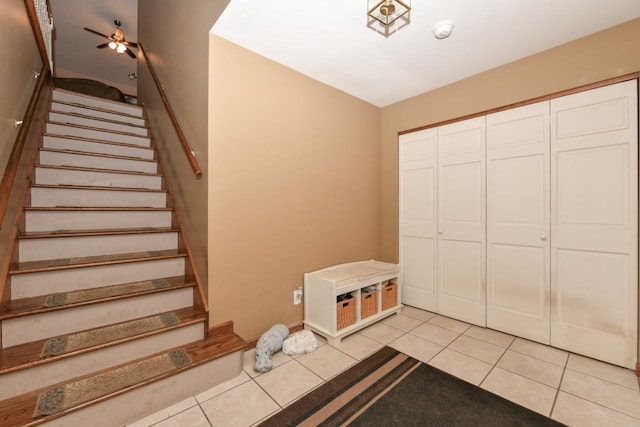 stairway featuring ceiling fan and tile patterned floors