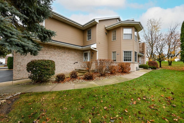 view of home's exterior featuring brick siding and a yard