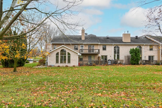 rear view of property featuring a yard, a chimney, and a balcony