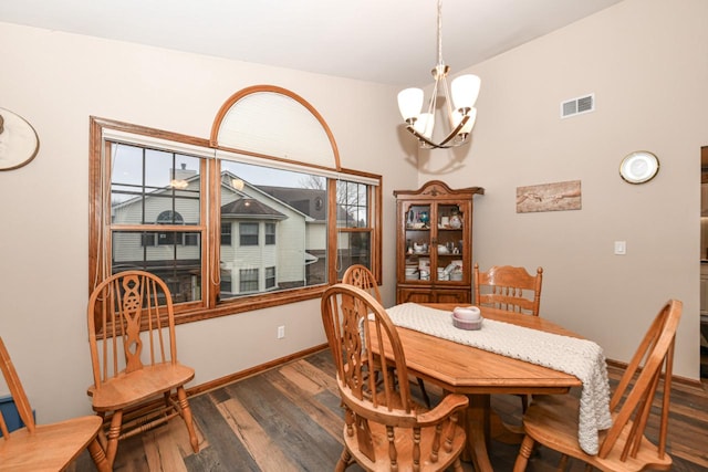 dining area with dark hardwood / wood-style flooring and an inviting chandelier