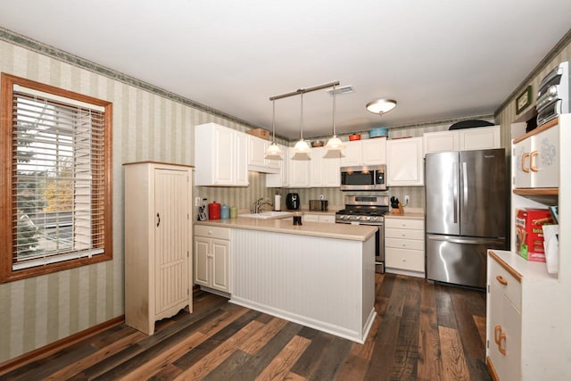 kitchen with stainless steel appliances, light countertops, a sink, and wallpapered walls