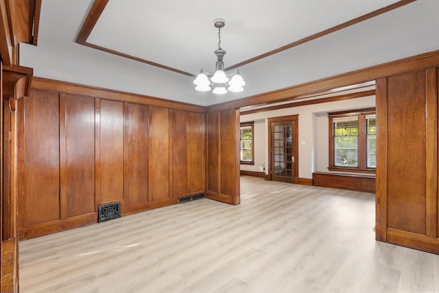 empty room featuring an inviting chandelier and light wood-type flooring