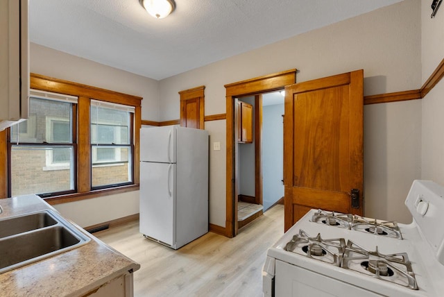 kitchen featuring a textured ceiling, white appliances, light hardwood / wood-style floors, and sink