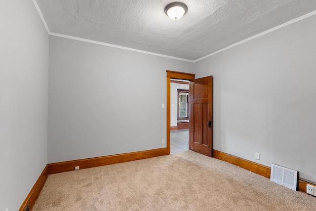 carpeted empty room featuring ornamental molding and a textured ceiling