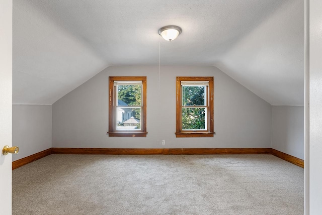 bonus room with carpet, a textured ceiling, and vaulted ceiling