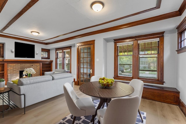 dining room with crown molding, a fireplace, and light hardwood / wood-style floors