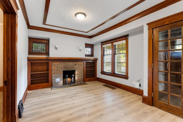 unfurnished living room featuring a fireplace, ornamental molding, a textured ceiling, and light wood-type flooring