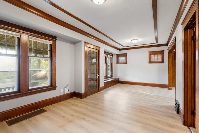 empty room with light hardwood / wood-style floors and crown molding