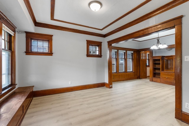 spare room with an inviting chandelier, ornamental molding, and light hardwood / wood-style flooring