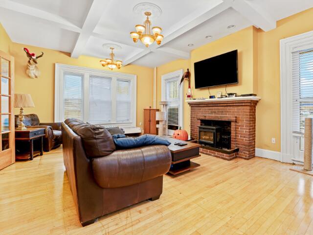 living room featuring a wood stove, light hardwood / wood-style floors, an inviting chandelier, and a healthy amount of sunlight