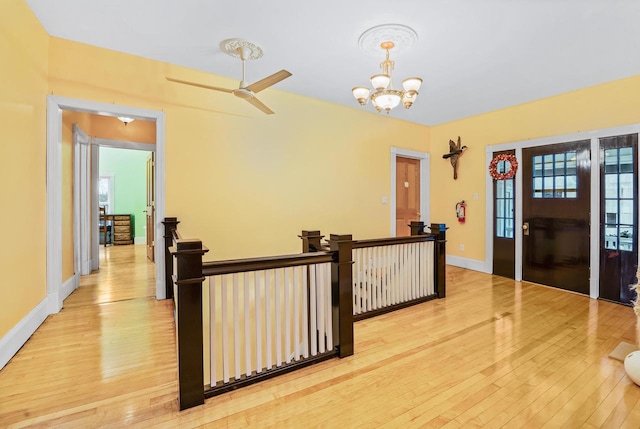 foyer featuring ceiling fan with notable chandelier and light wood-type flooring