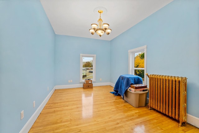 interior space featuring radiator heating unit, an inviting chandelier, and wood-type flooring