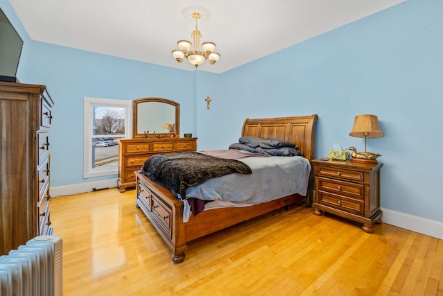 bedroom featuring radiator heating unit, an inviting chandelier, and light hardwood / wood-style flooring