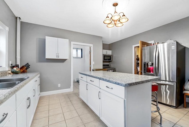 kitchen with white cabinetry, stainless steel appliances, pendant lighting, a kitchen bar, and light tile patterned flooring