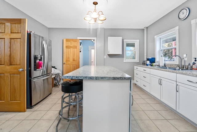 kitchen featuring hanging light fixtures, stainless steel fridge with ice dispenser, light tile patterned floors, a kitchen island, and white cabinetry