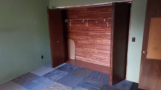 unfurnished bedroom with wood walls and a closet