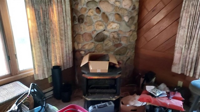 living area with a baseboard heating unit and wood walls