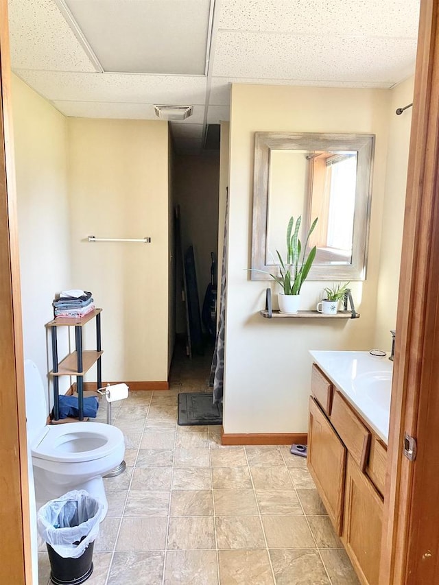 bathroom with vanity, toilet, and a paneled ceiling