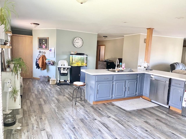 kitchen featuring kitchen peninsula, a kitchen breakfast bar, stainless steel dishwasher, blue cabinetry, and light hardwood / wood-style flooring