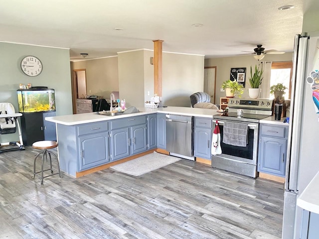 kitchen featuring kitchen peninsula, light wood-type flooring, stainless steel appliances, and blue cabinets