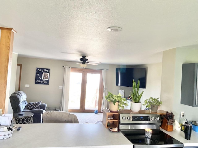 kitchen featuring french doors, a textured ceiling, ceiling fan, carpet floors, and stainless steel electric range oven