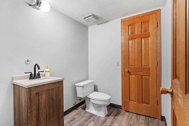 bathroom with hardwood / wood-style floors, vanity, a textured ceiling, and toilet