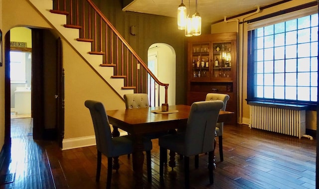 dining space with dark hardwood / wood-style floors, radiator heating unit, and a chandelier