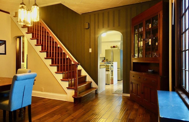 interior space with a chandelier, wood-type flooring, ornamental molding, and wood walls