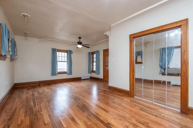 unfurnished living room featuring ceiling fan, wood-type flooring, and a baseboard radiator