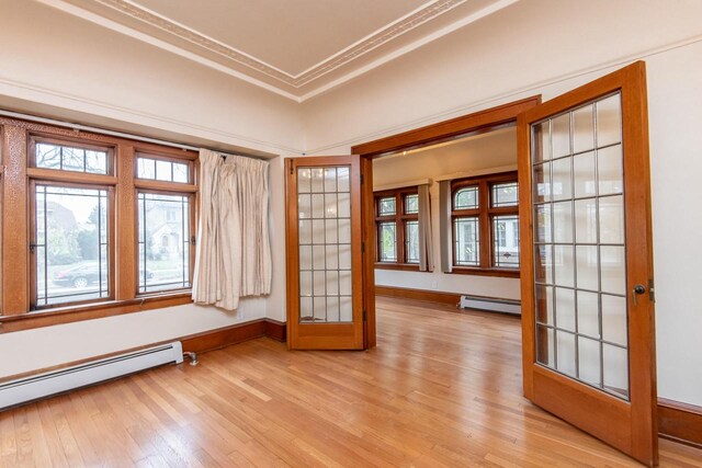 empty room with light hardwood / wood-style floors, baseboard heating, and french doors