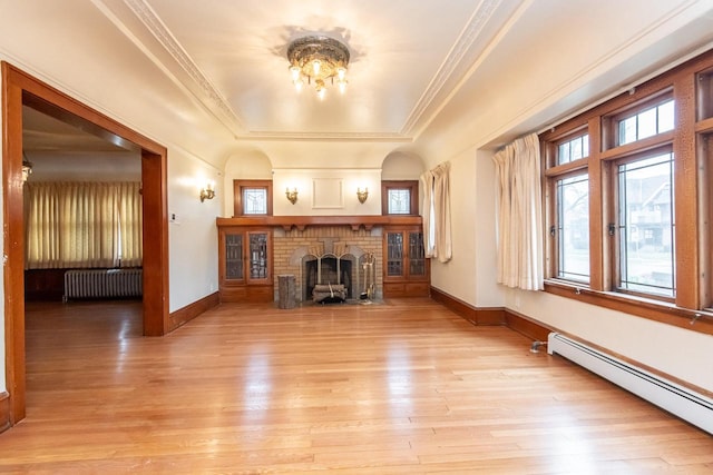 unfurnished living room featuring radiator, a brick fireplace, a raised ceiling, a baseboard heating unit, and light wood-type flooring