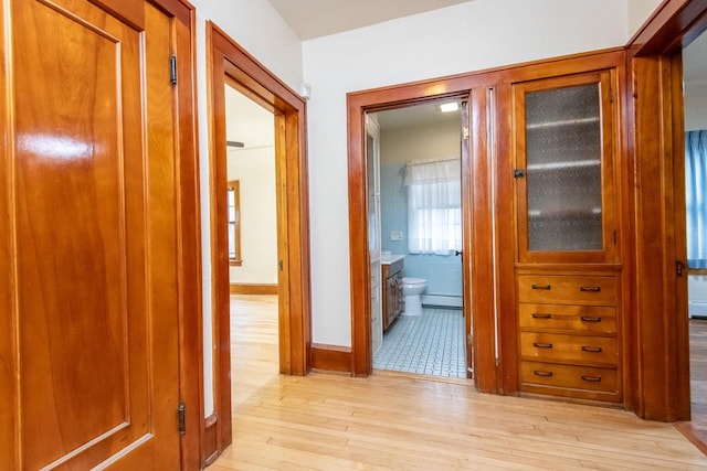 corridor with light hardwood / wood-style flooring and a baseboard radiator