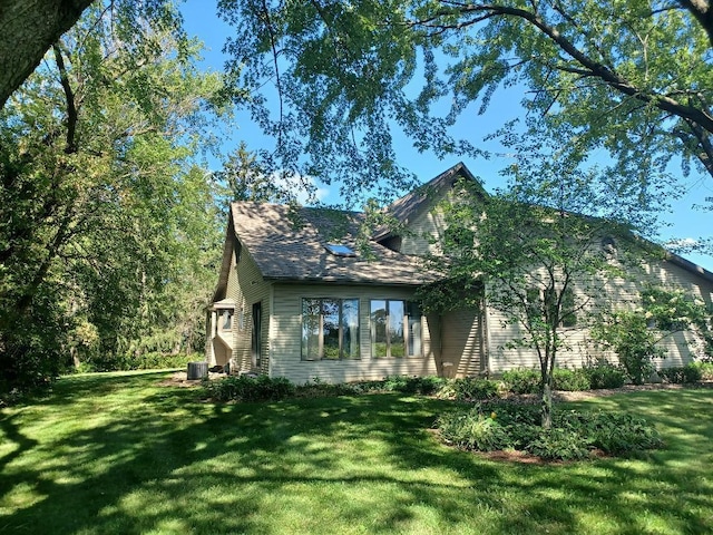 view of side of property with central AC unit and a lawn