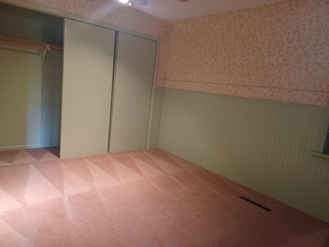 unfurnished bedroom featuring light carpet and a closet