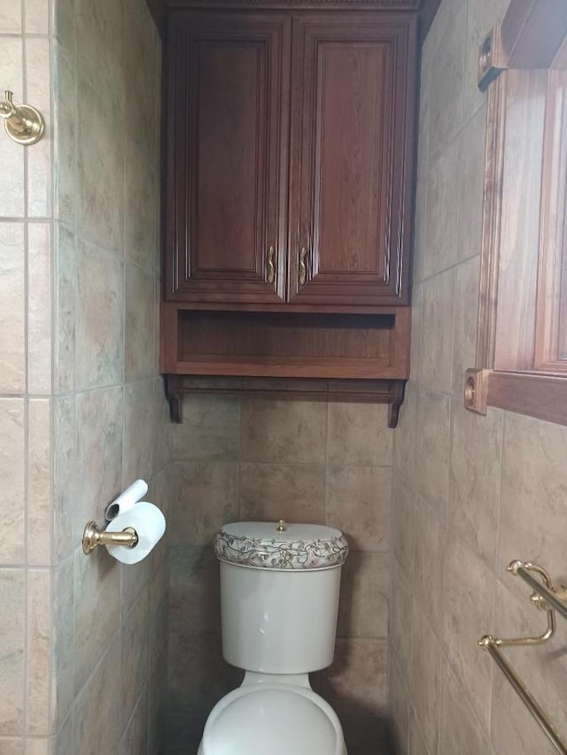 bathroom with tile walls and toilet