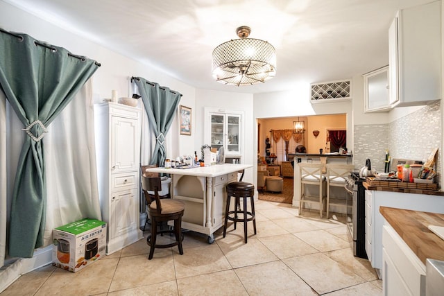 330 E Locust St, Milwaukee, WI 53212 - kitchen featuring white cabinets, a breakfast bar, light tile patterned floors, and a chandelier