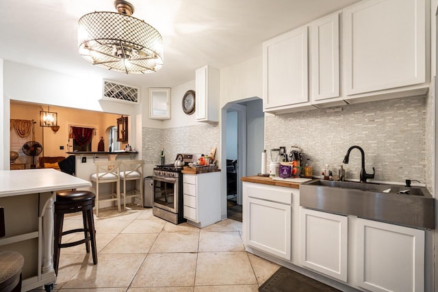 330 E Locust St, Milwaukee, WI 53212 - kitchen with stainless steel gas range oven, a sink, backsplash, and white cabinetry