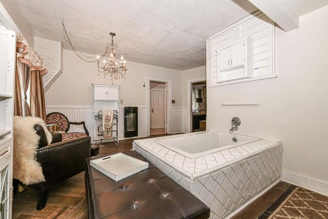 interior space with a notable chandelier, hardwood / wood-style floors, tiled bath, and a textured ceiling