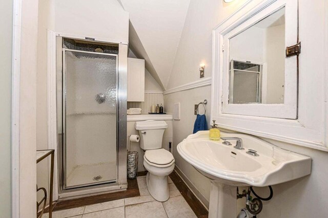 bathroom featuring walk in shower, lofted ceiling, toilet, and tile patterned flooring