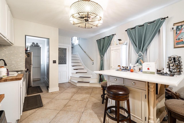 330 E Locust St, Milwaukee, WI 53212 - kitchen with a kitchen breakfast bar, decorative backsplash, light tile patterned floors, a chandelier, and light countertops