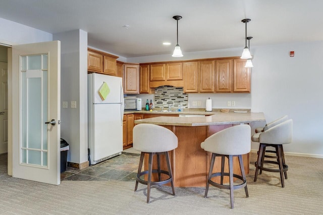 kitchen with white appliances, kitchen peninsula, decorative light fixtures, a kitchen bar, and carpet floors