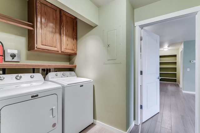 washroom with washing machine and clothes dryer, electric panel, cabinets, and light wood-type flooring