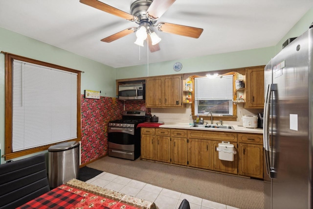 kitchen with appliances with stainless steel finishes, light tile patterned floors, ceiling fan, and sink